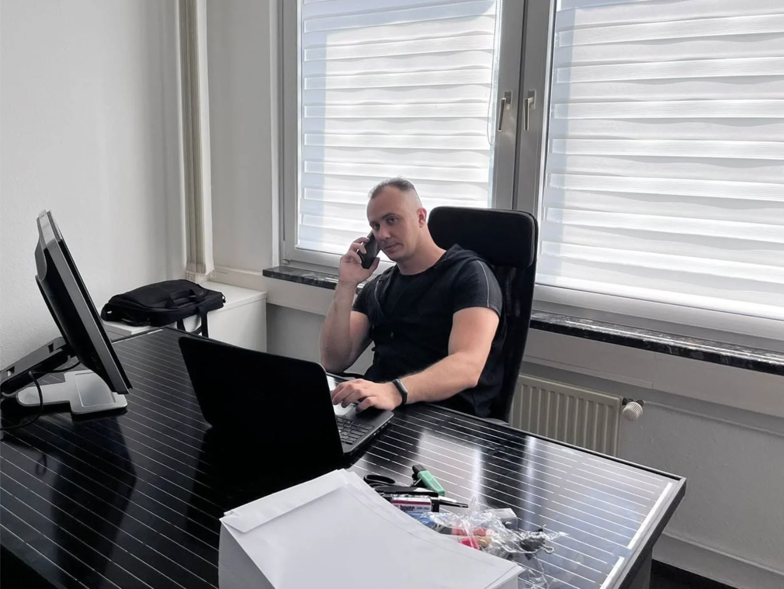 Dmytro Grebeniuk, właściciel DGinstal-bud, przy biurku w trakcie rozmowy z klientem